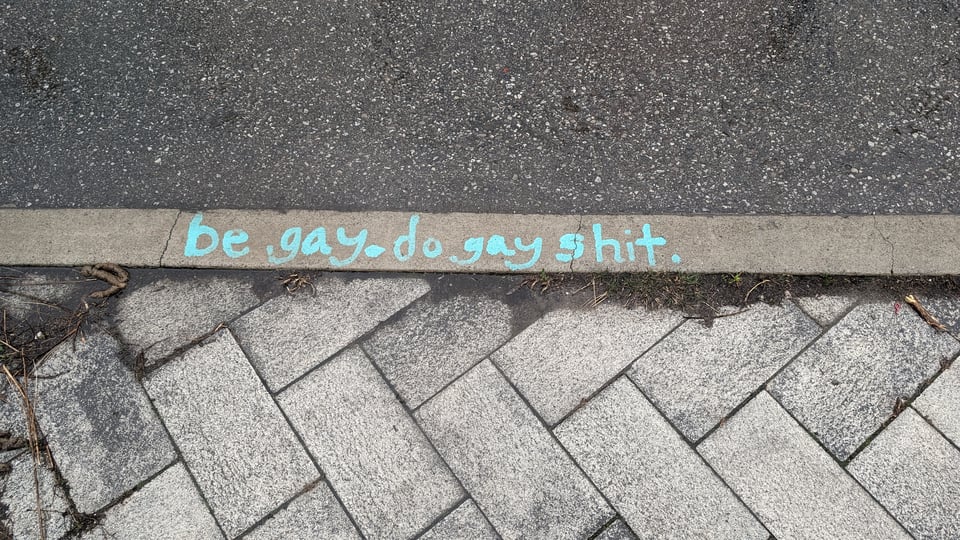 sidewalk grafitti in kind of a mint color reading "be gay. do gay shit."