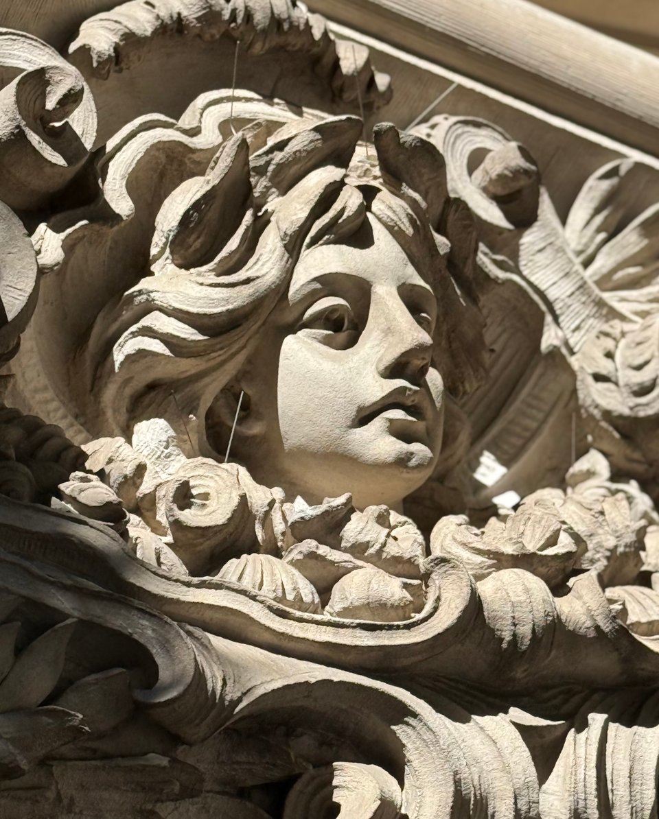 stone carving of a woman's face, flowers and other decorative elements