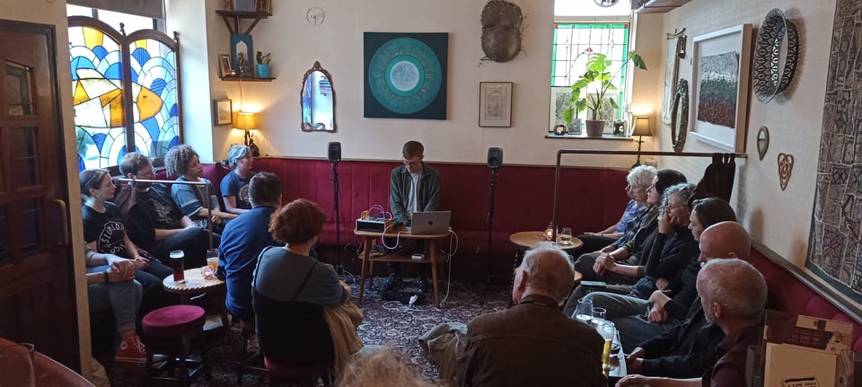 A musician performs electronic music in a small pub.