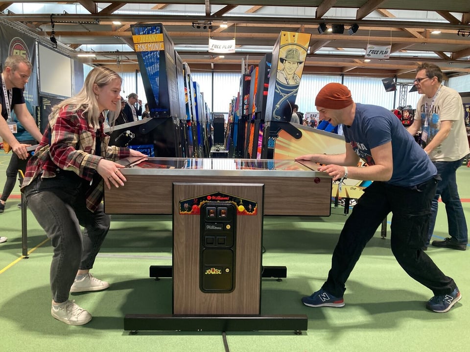 Two persons playing a 2-player pinball machine.