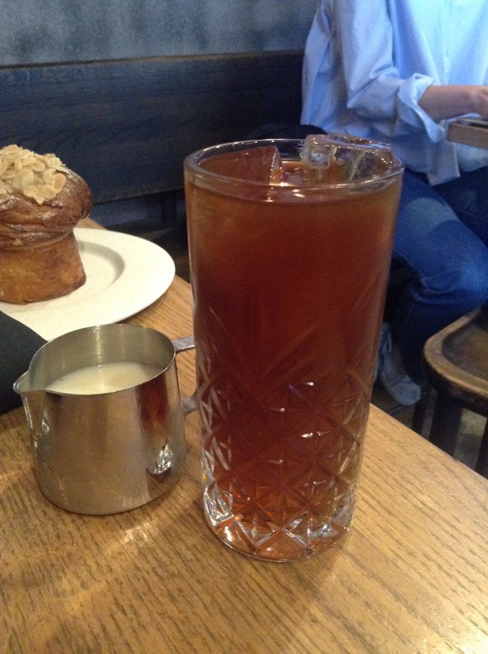 Iced coffee in a cut crystal glass with a small metal pitcher of milk.