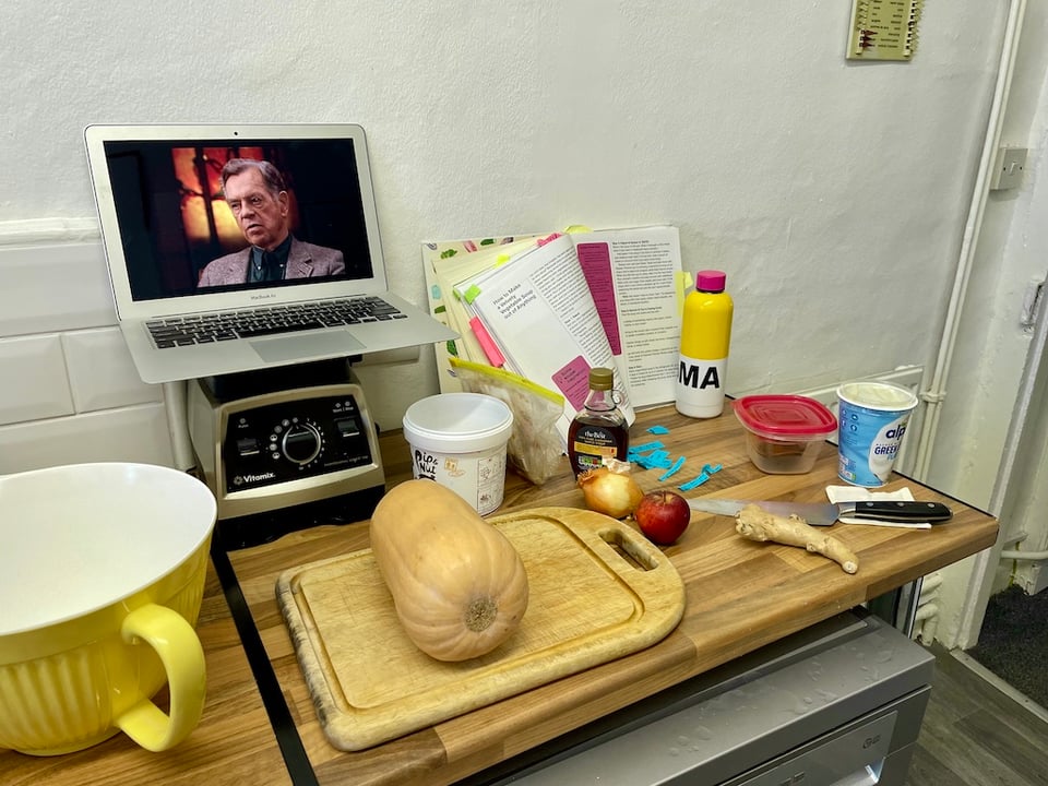 A butternut squash and various ingredients for soup.