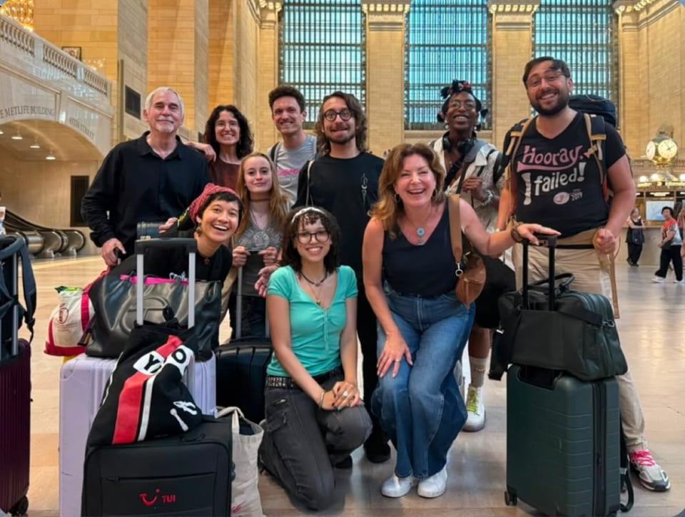 a group picture of people at a train station with suitcases