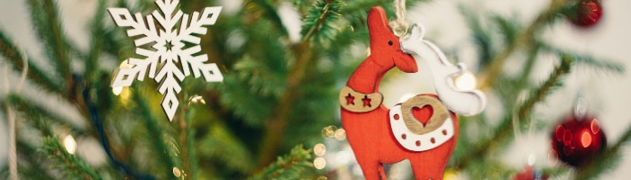 A close-up of a red reindeer ornament and lights on a Christmas tree
