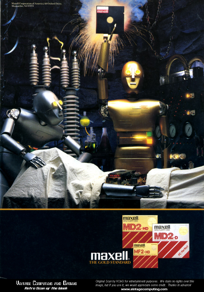 A gold robot is standing in a laboratory, next to a silver robot on an operating table. The gold robot is holding a 5.25" floppy disk overhead while another silver robot stands nearby crouched over like Igor from Frankenstein.