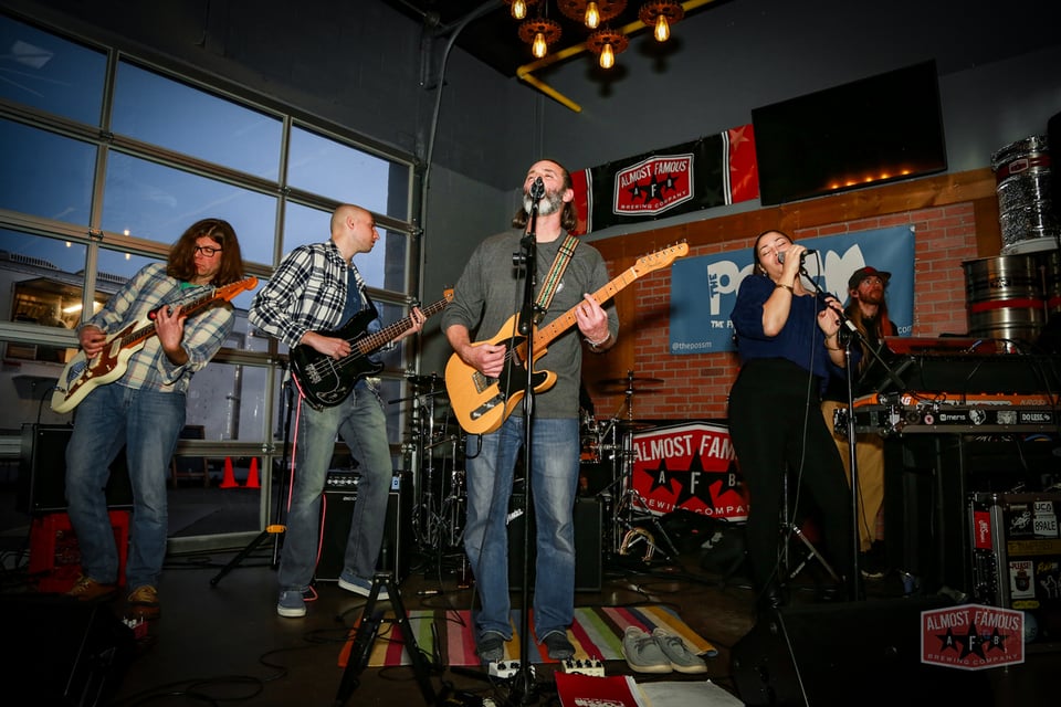 Five musicians in a rock band play together onstage.