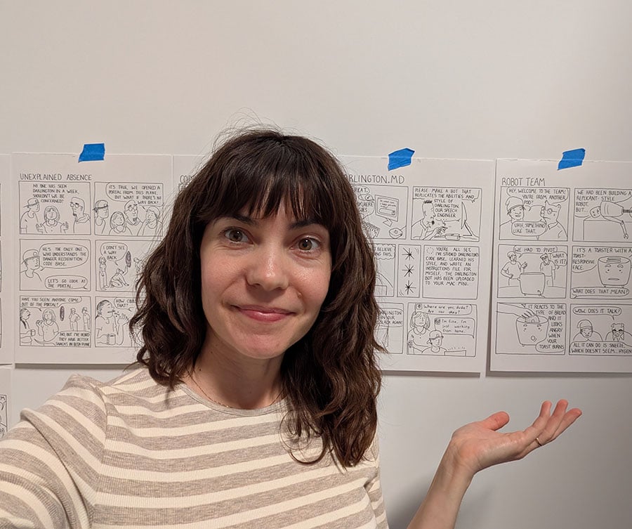 Photo of the artist in front of finished comics pages
