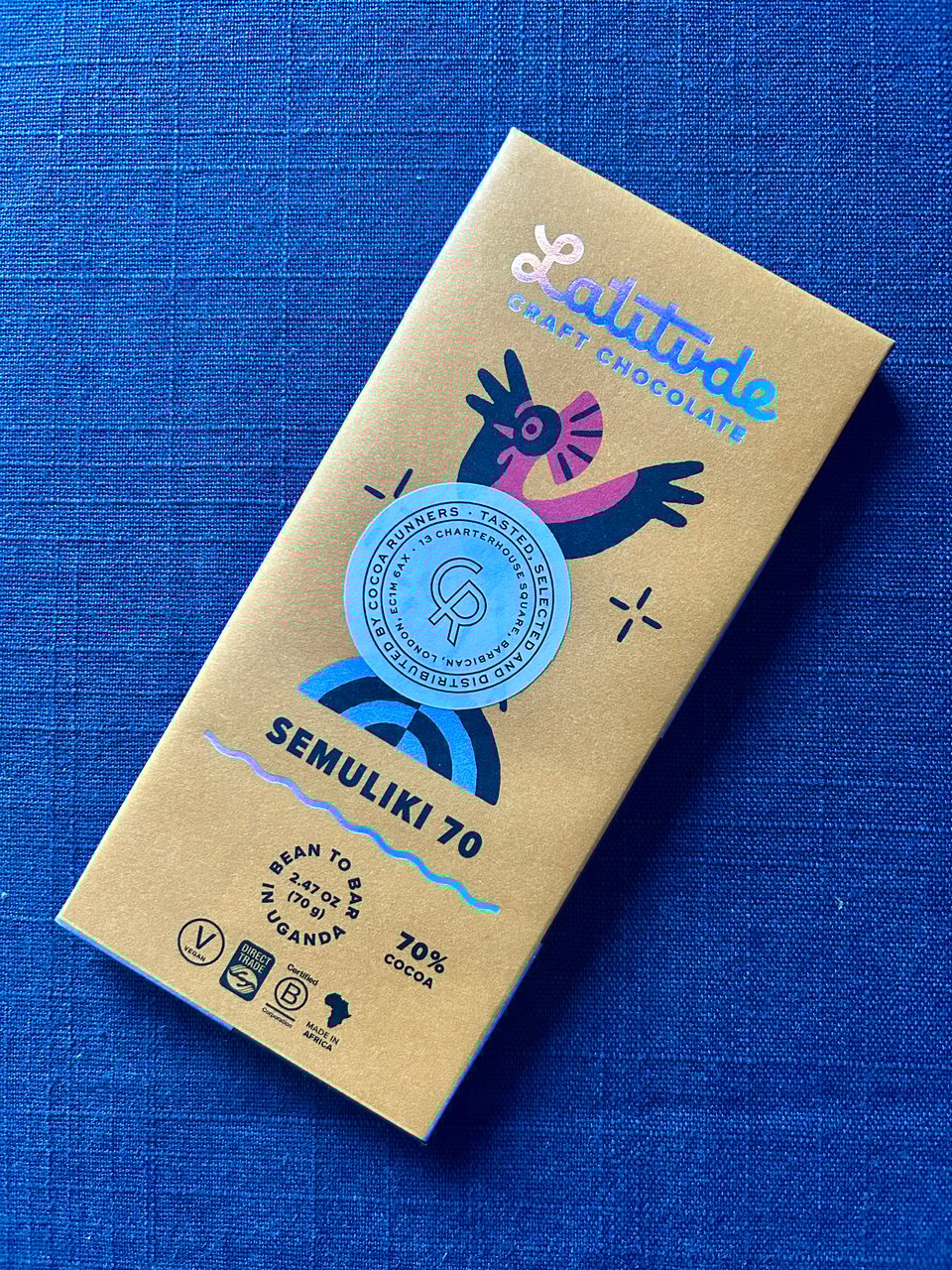 A yellow bar of 70% cocoa Latitude chocolate, grown and made in Uganda is lying on a blue tablecloth. Image by Rowan Ambrose.