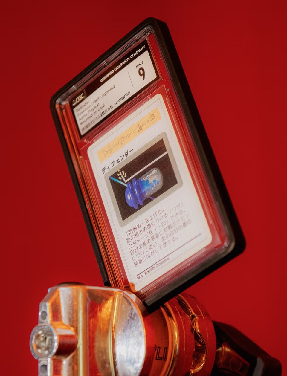 A graded Japanese Pokémon trading card encased in a clear plastic holder labeled “Mint 9” by Certified Guaranty Company. The card features Japanese text and an illustration of a blue capsule-shaped object against a red background, with the holder mounted on a shiny metallic clamp