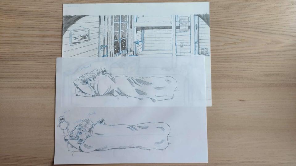 Picture of three sheets of paper on a wooden surface. One it the background sketch seen above, the two other ones, on tracing paper, show Lucie in her bed, in two different positions.