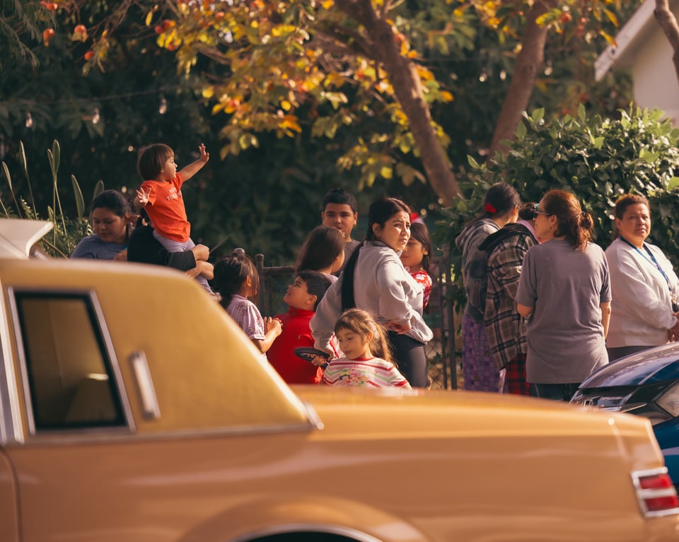 Image of families and their kids waiting in line to receive toys at Litostyle 2025 Christmas toy giveaway, with one of the lowriders in the foreground.