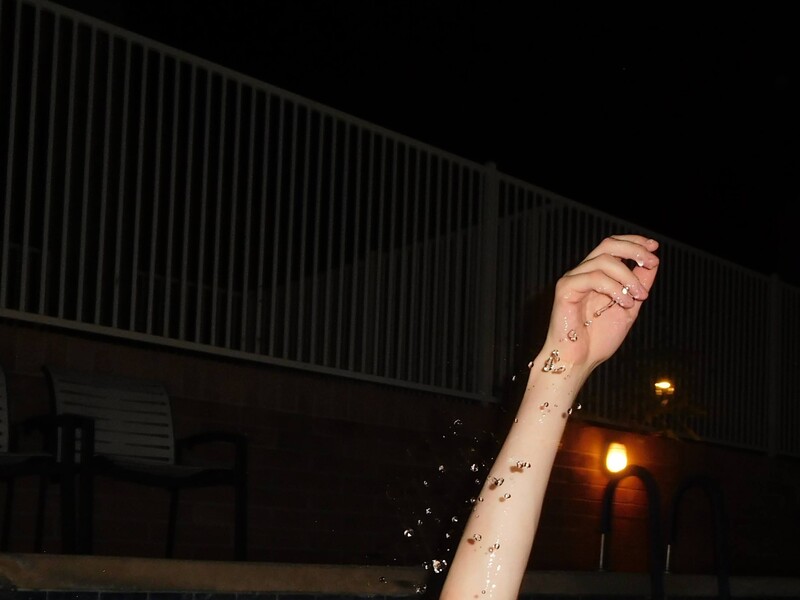 An arm emerging from a swimming pool at night