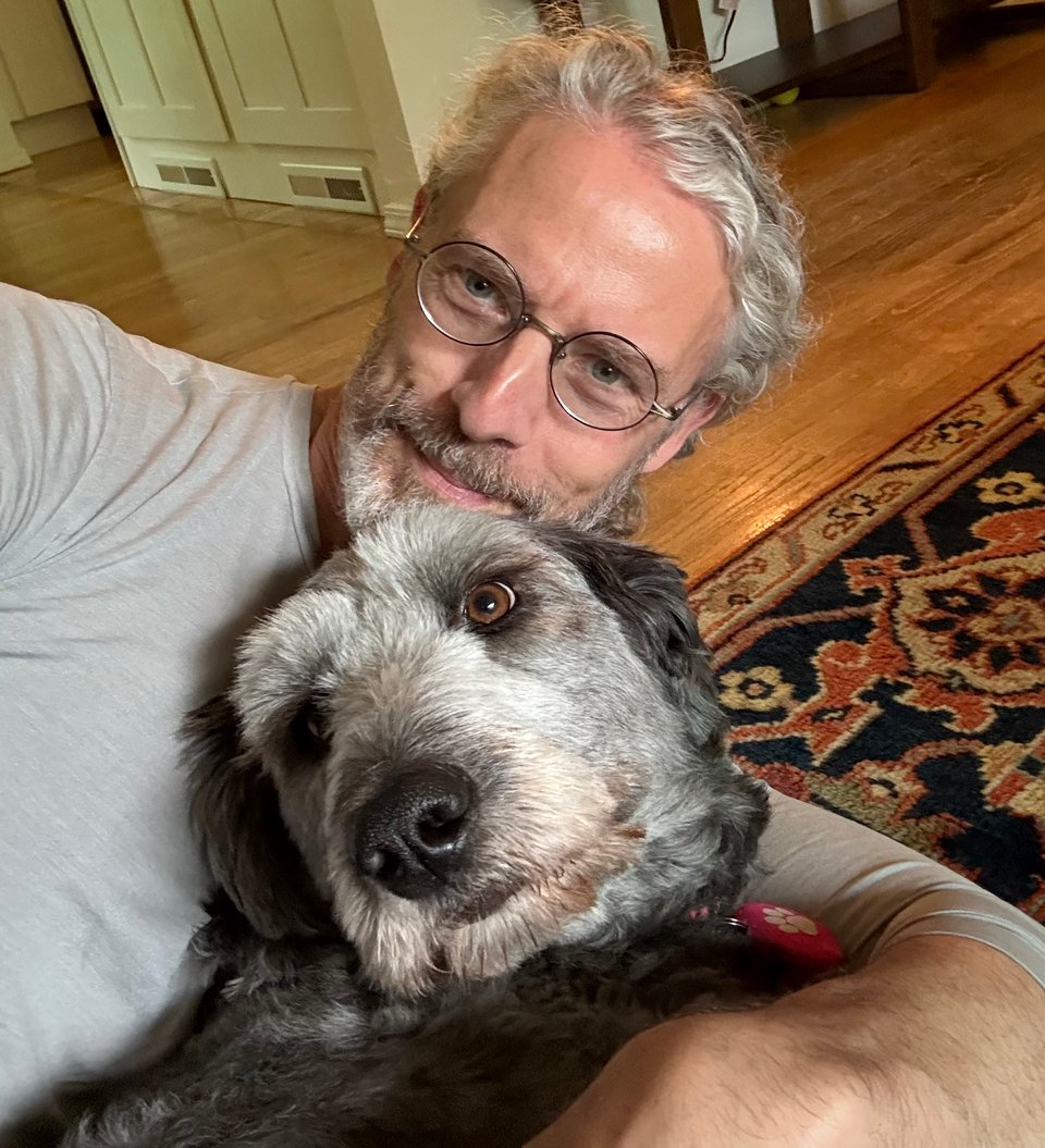 selfie photo of white man with glasses holding a gray Aussiedoodle who looks a little put-upon