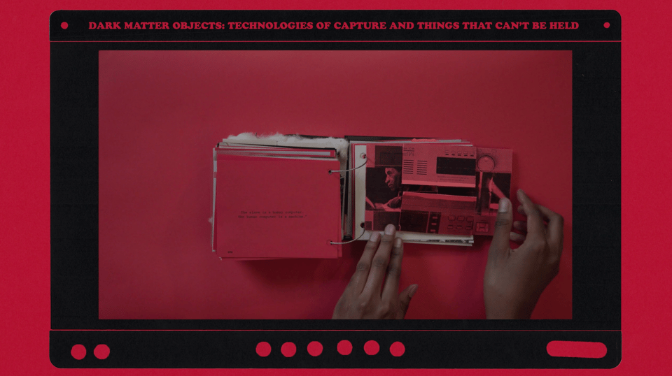black hands turning the page of a small booklet with red pages and red background