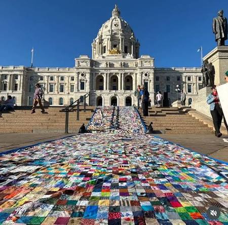Photo of a massive patchwork quilt spread over the steps of the Minnesota State Capital building on September 22, 2026. Image source: Instagram