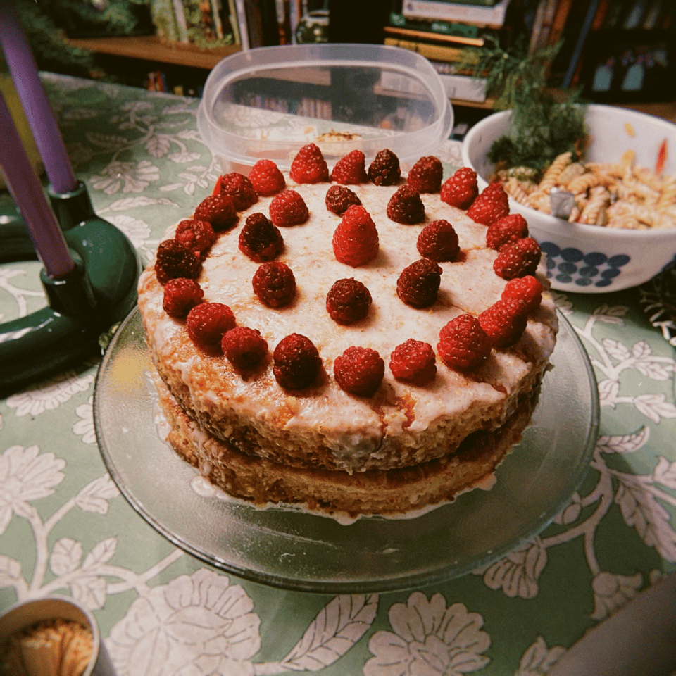 A layered cake with raspberries on top.