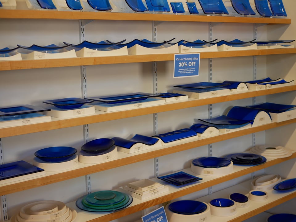 a collection of ceramic slump molds, almost all of which have a finished slumped piece in them to show what the finished pieces made with the mold will look like