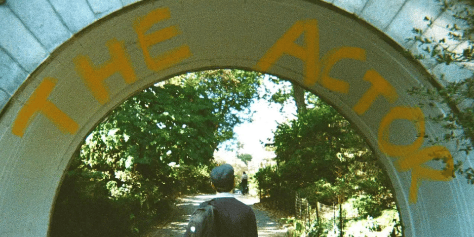 A man walks under a bridge.