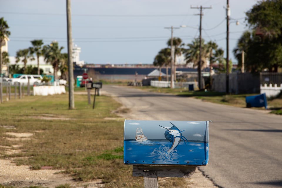 A mailbox with a kingfisher, with an oil tanker in the background
