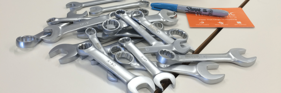 Photograph of a pile of spanners on a table next to a Sharpie pen.