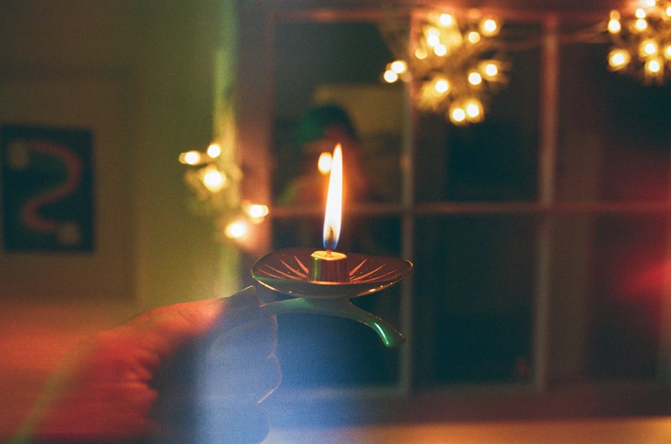 beth holding up a tiny candle in front of a mirror