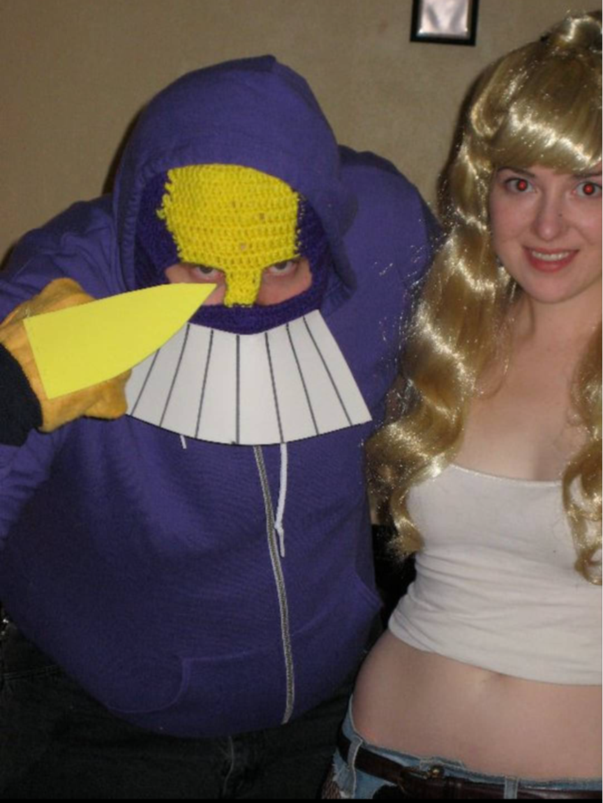 Jex, maybe 15 years ago, wearing a purple American Apparel hoodie, a crocheted mask with foam teeth, and yellow gloves with foam claws, dressed as the Maxx. Their partner is wearing a long blond wig, a white tank top, and low rise jeans, like Julie Winters from The Maxx comics.
