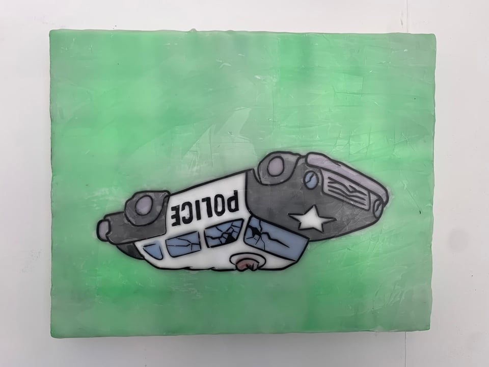 Overturned, and smashed police car on a green background.