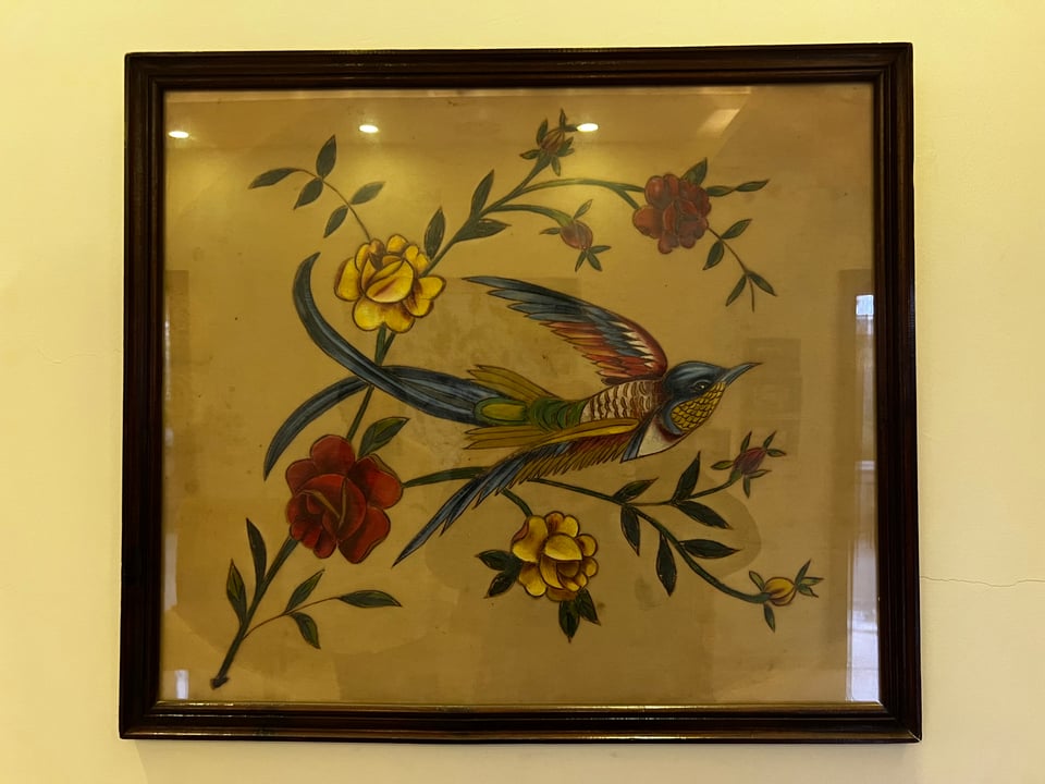 A framed drawing of a bird with flowers