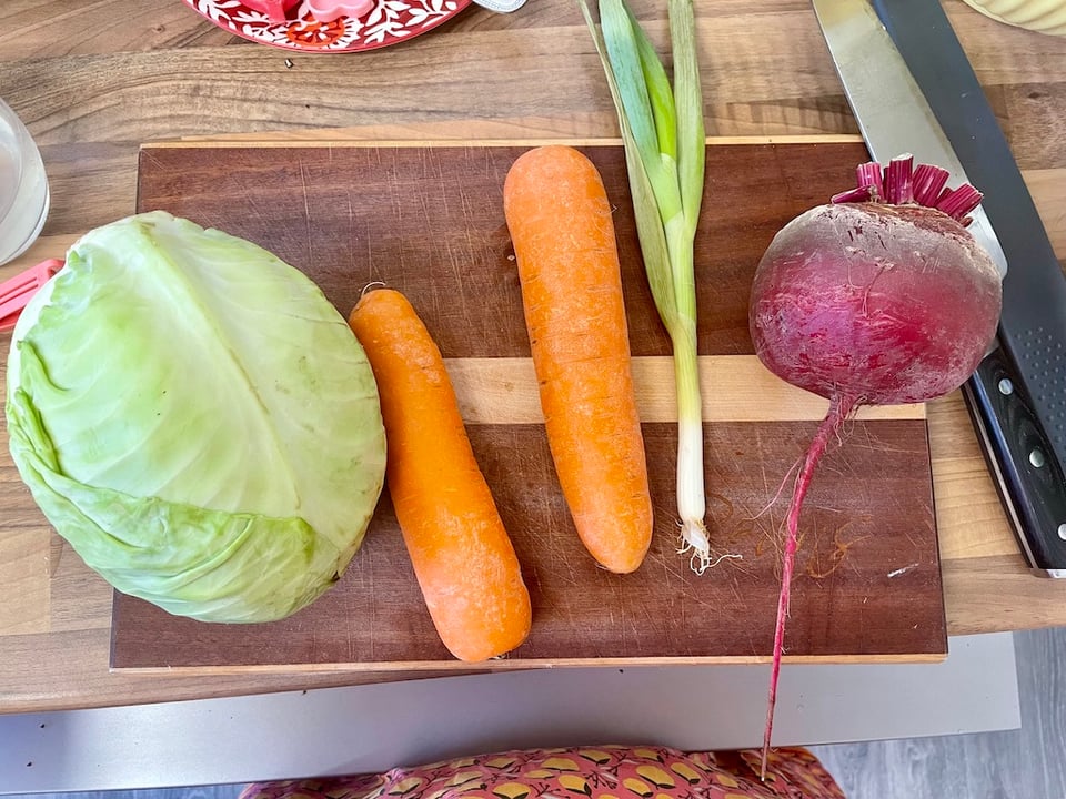 A cabbage, carrots, spring onion and giant beet on a chopping board