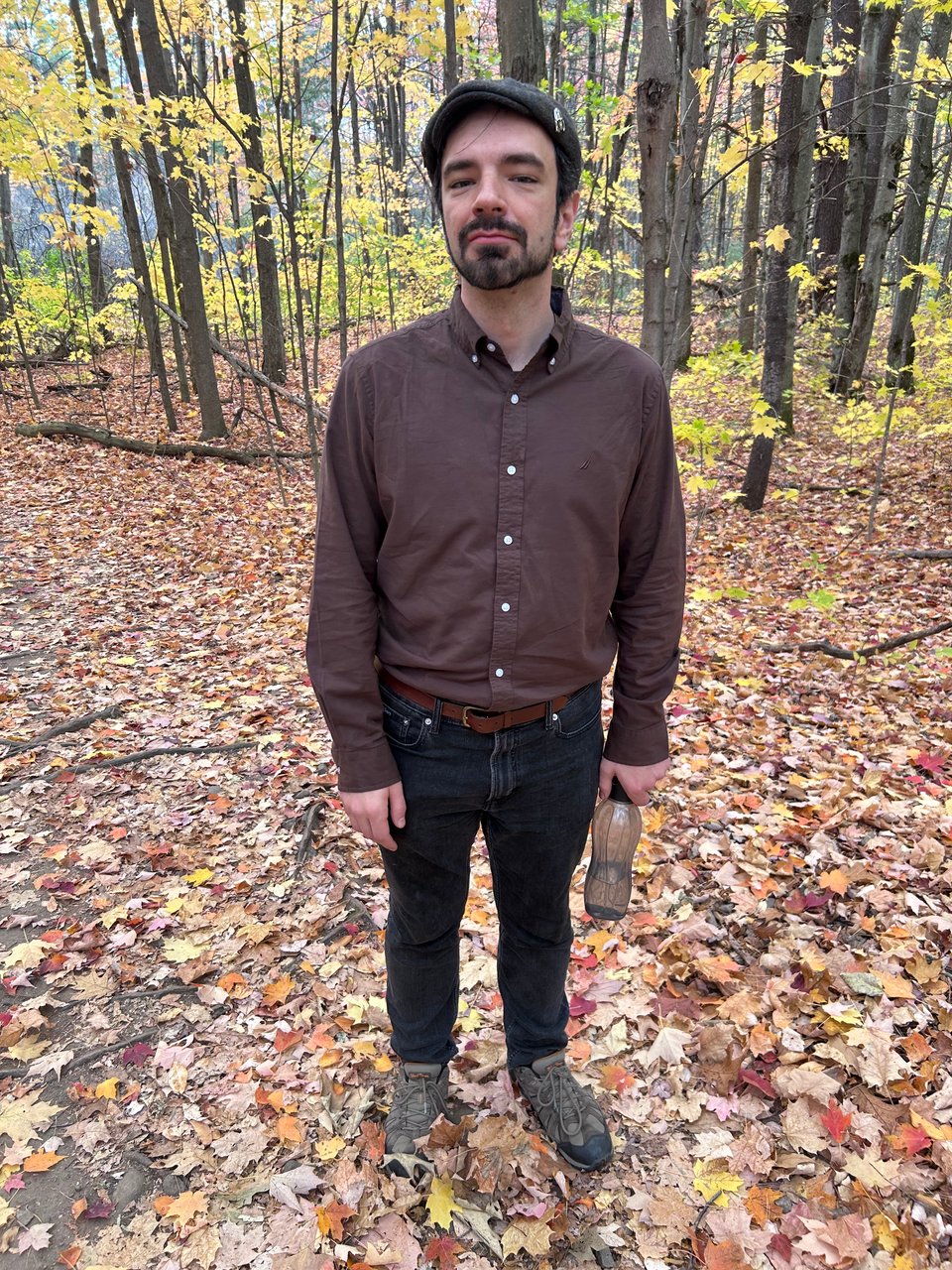 I am standing on a trail covered in orange, red, and yellow leaves.