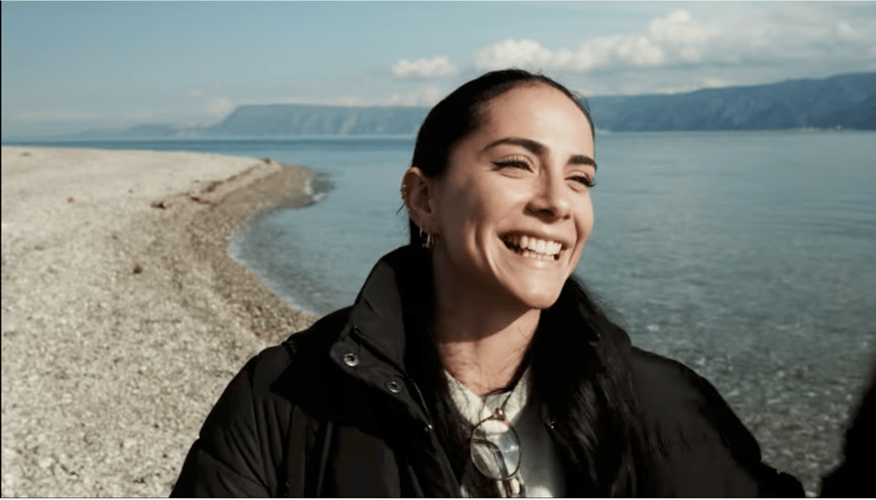 Image description: A person smiles on a beach in Messina, Sicily