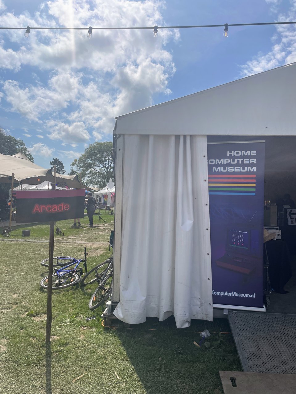 A large white tent is set up and the banner of the "Home Computer Museum" is seen inside.