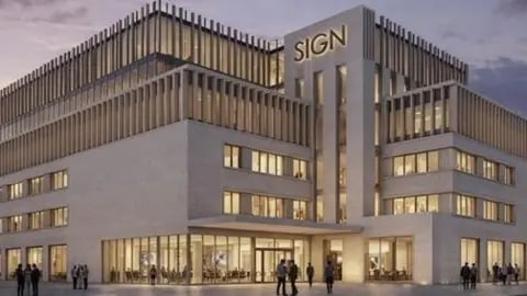 A 1950s department store at an imagined dusk. The building is made of two horizontal blocks joined by a taller tower. There are ribbons windows and a large foyer. At the upper levels, the 1980s roof extensions have gained vertical brise soleils that rise above the roof line.