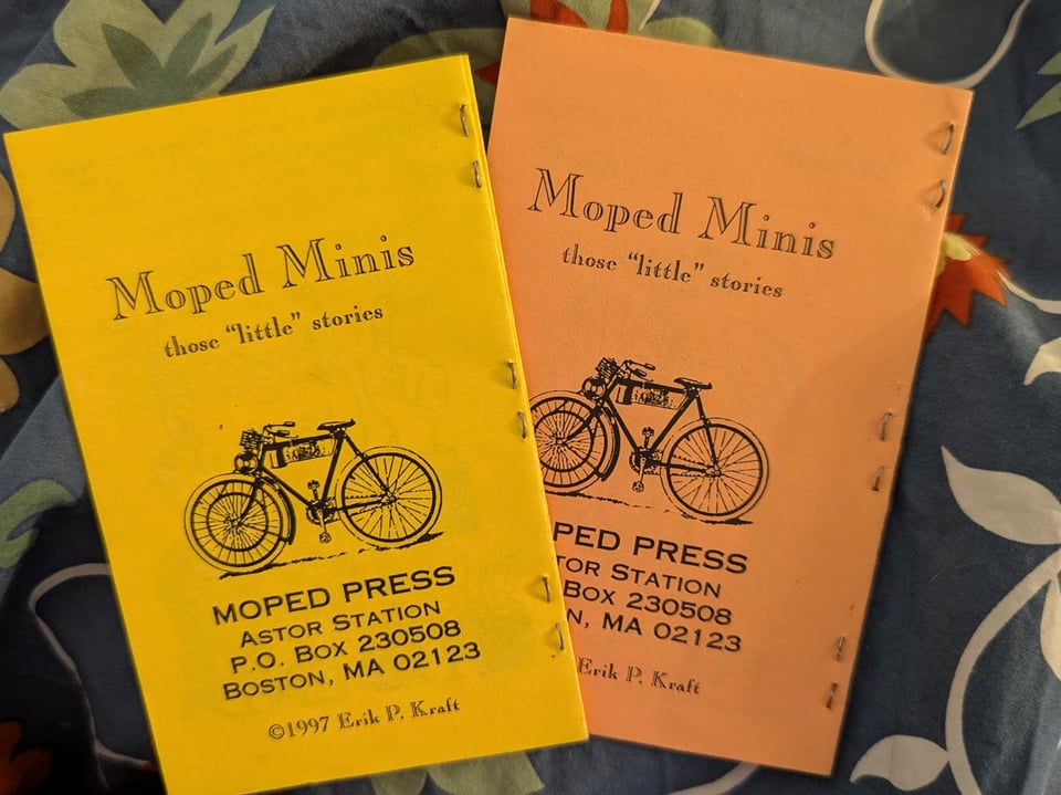 a photo of two mini-zines, called moped minis. one is yellow and one is orange. the feature an illustration of bicycle on the cover.