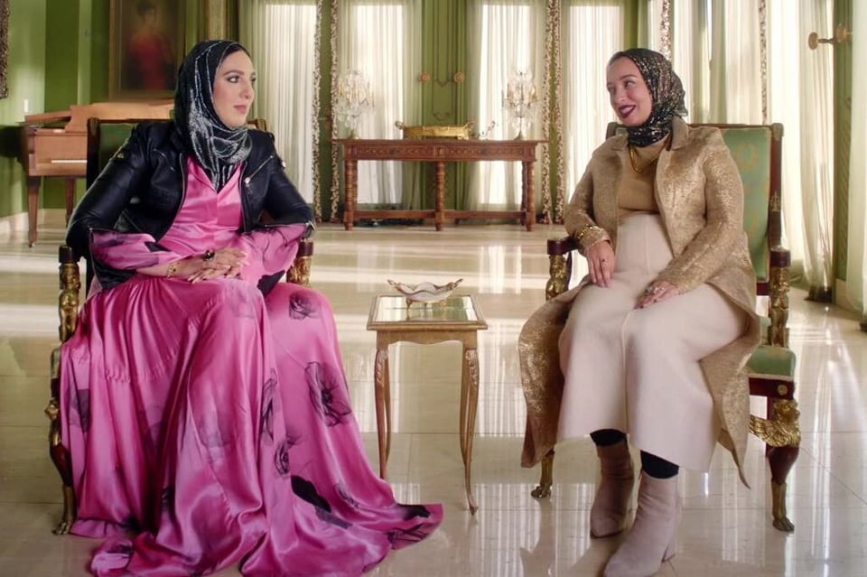 Yasmin Elhady and Hoda Abrahim of Muslim Matchmaker seated in chairs wearing their signature opulent modest clothing in an opulent room