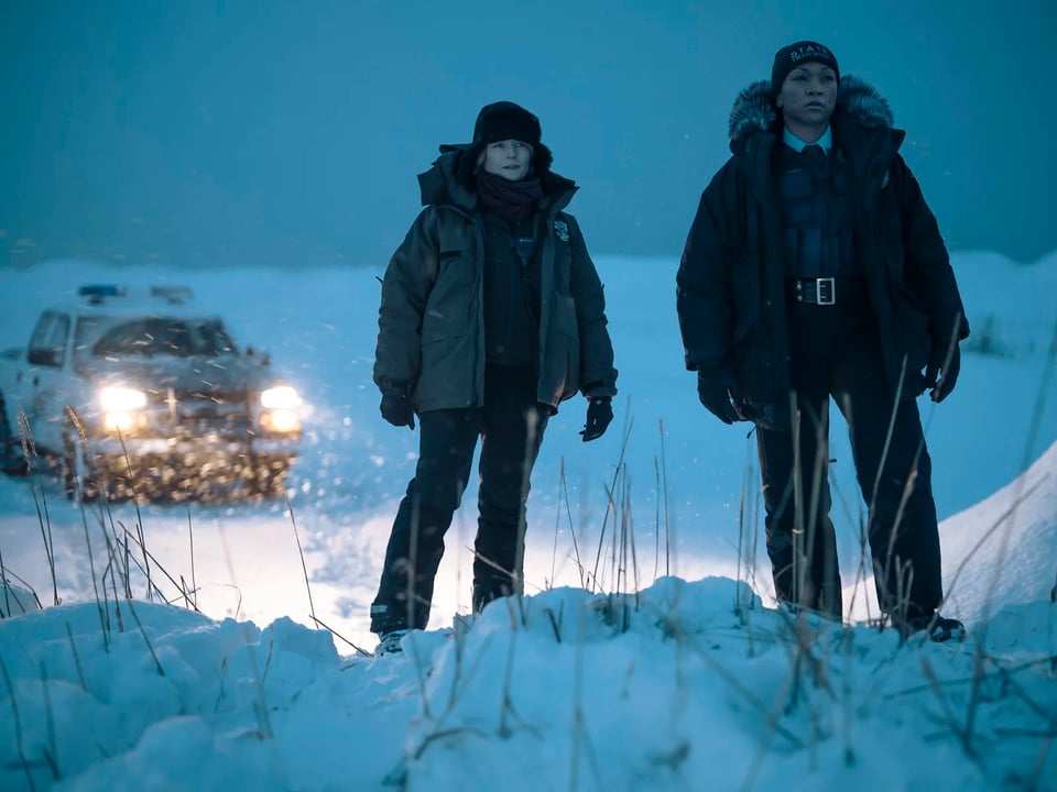 The two main characters of True Detective stand on a snow bank in a blizzard.