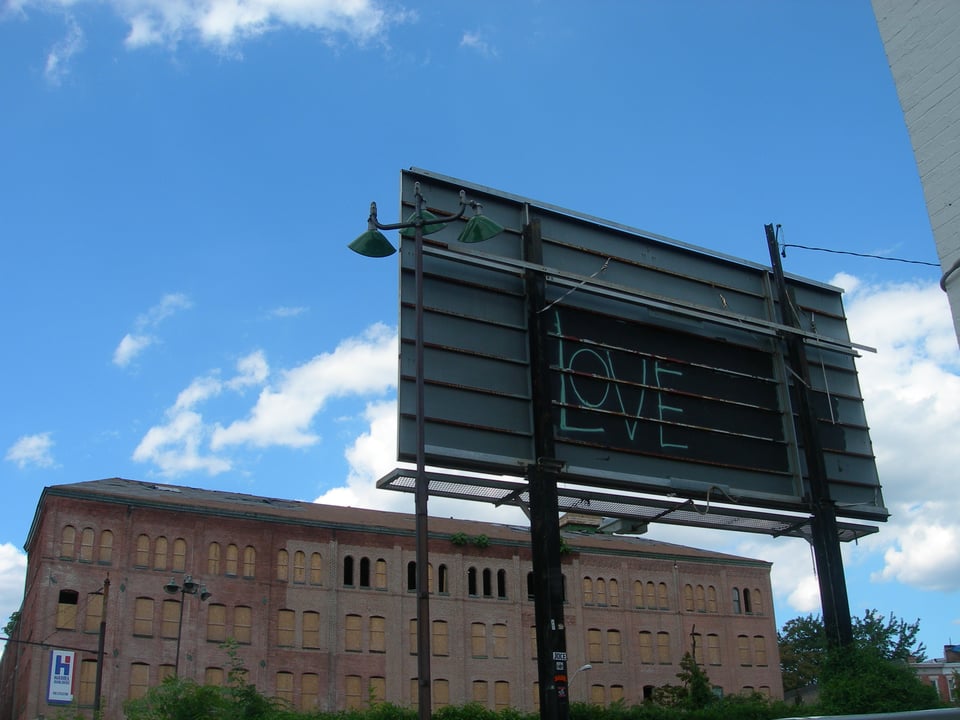It's a billboard and on the back it says LOVE. The sky is blue and there's a warehouse in the background.