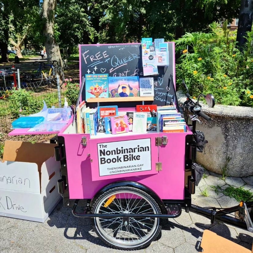 The Nonbinarian Book Bike is stocked with free LGBTQIA+ books, and beside it is a box for donations