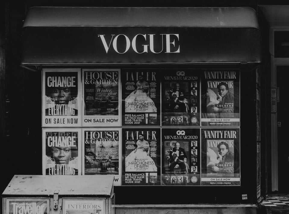 A black-and-white photo of a newsstand, with several magazine covers as posters. Photo by Toa Heftiba on Unsplash