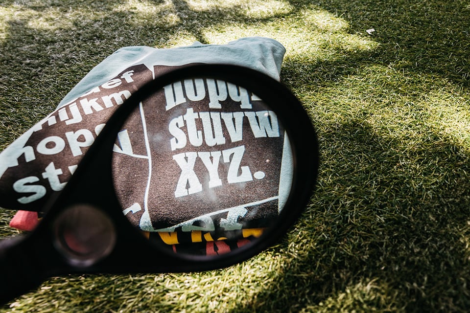 Stack of XYZ Type t-shirts on astroturf, viewed through a magnifing glass, empahsizing XYZ.