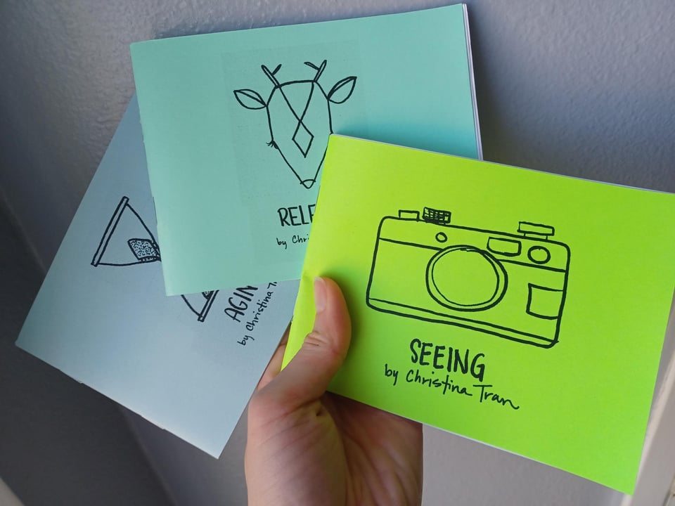 hand holding three quarter-page sized zines