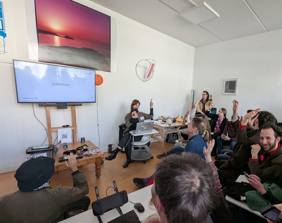 A speaker asks for a show of hands, and the audience - many laughing - oblige.