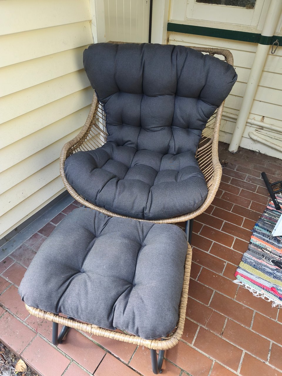 the same kind of chair, rattan with metal legs and gray seat covers, on a small porch