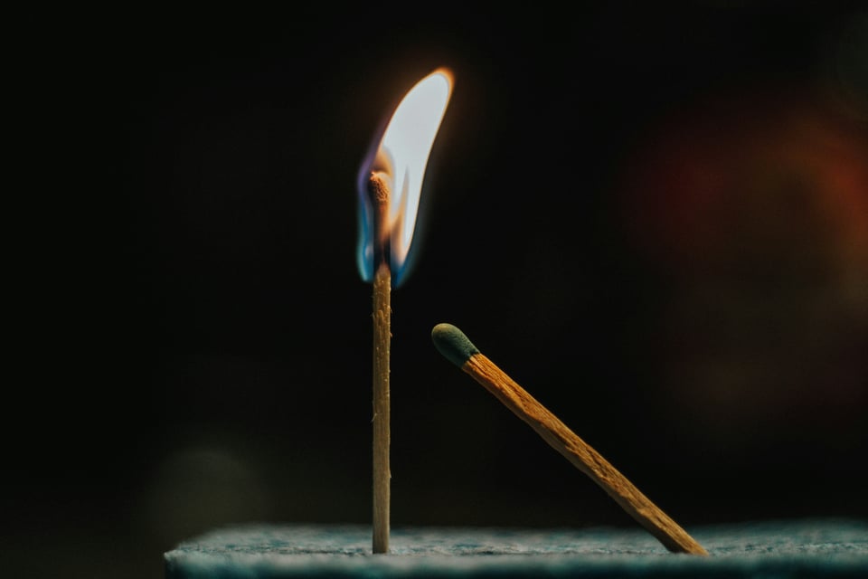 Image of two match sticks, one on fire and one unlit and leaning towards the flame.