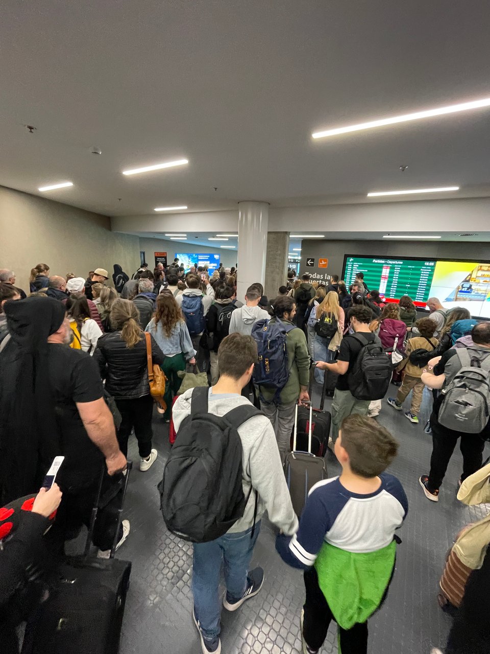 A mass of people walk together through the airport.
