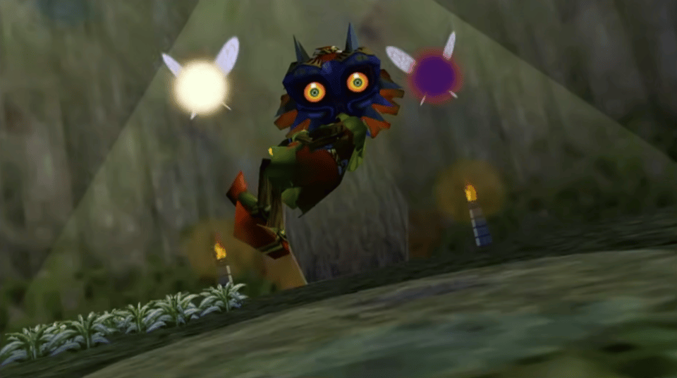 A 3D-rendered figure floats in front the the camera, which is held at an odd angle from the viewer's perspective. Two orbs of light -- fairies -- hover there. The figure has a mask with glowing eyes. In the background, there are muddy textures, torches, pointed blades of grass.