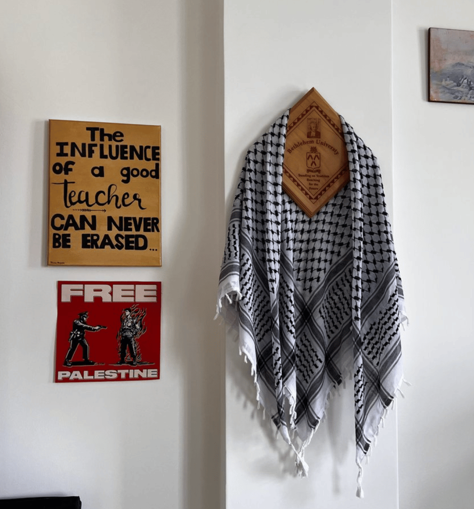 Two signs on the wall, and a keffiyeh hanging on a plaque