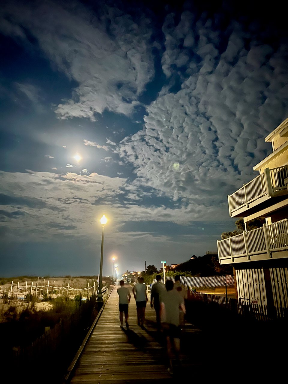people walking on a boardwalk at night