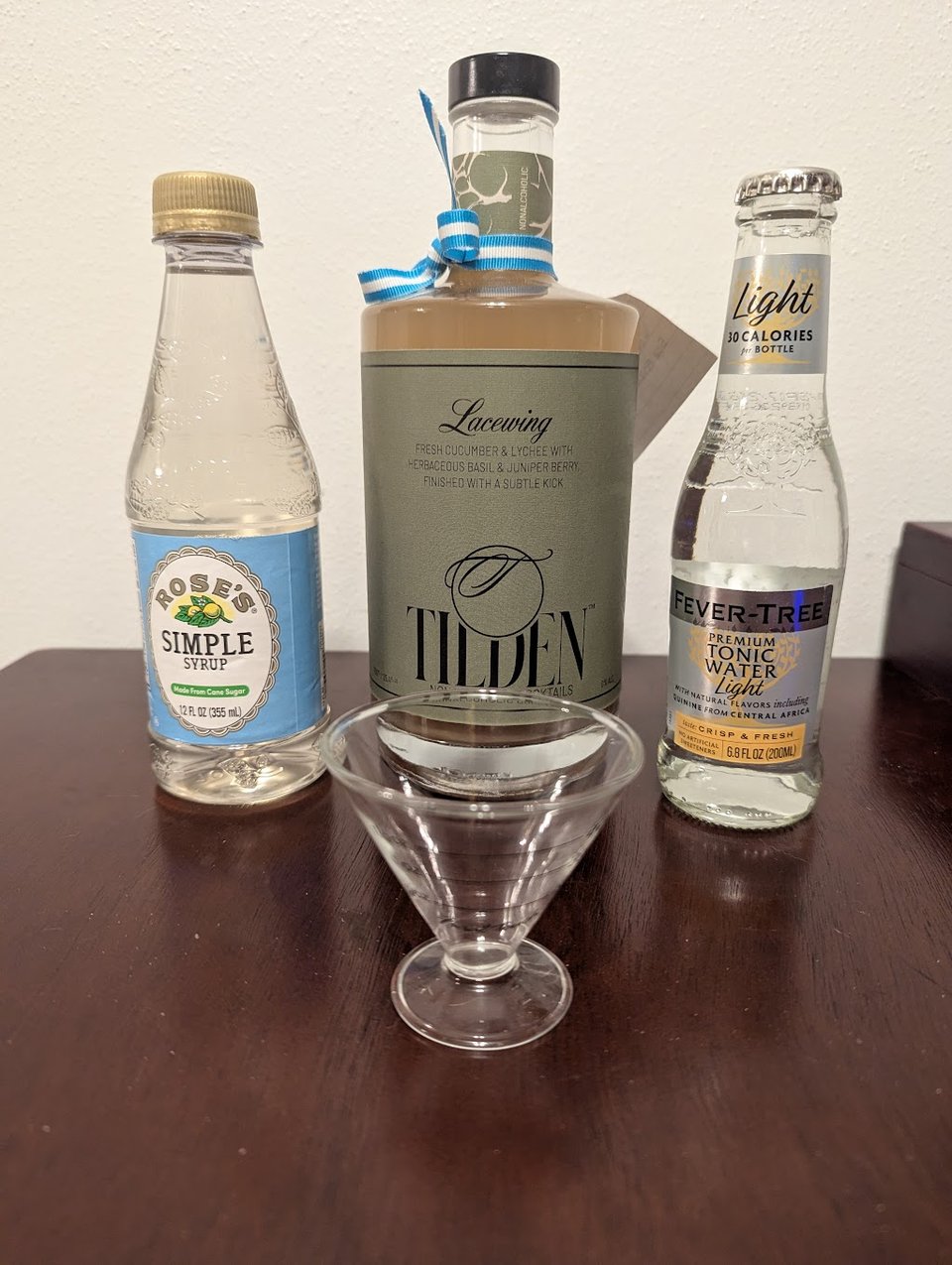 A bottle of sweet syrup, a bottle of Tilden, a bottle of tonic water, and a measuring glass.
