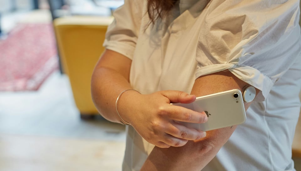 photo of a woman scanning blood glucose with a continuous glucose monitor